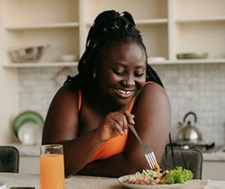 Woman smiling while eating healthy lunch at home