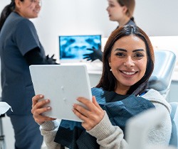 Patient smiling while holding mirror in treatment chair
