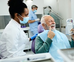 Man smiling while looking at reflection in mirror at dental office