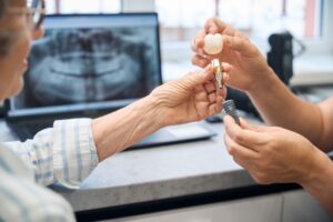 Dentist using model to explain dental implants